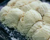 Surowe, cienkie nitki makaronu ułożone w porcje na ciemnej tacy. Czy pies może jeść makaron?